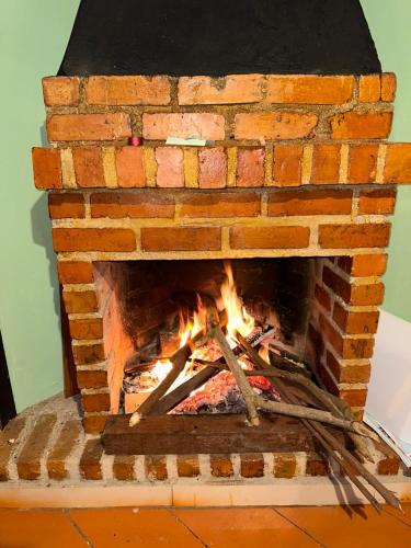 a brick fireplace with a fire in it at Cabaña el bucanero in Pasto