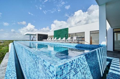 a swimming pool with blue tiles on the side of a house at Infinity Pool rooftop wifi Tulum in Tulum