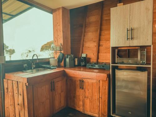 een keuken met houten kasten en een roestvrijstalen koelkast bij Peregrino Glamping 1 in Medellín