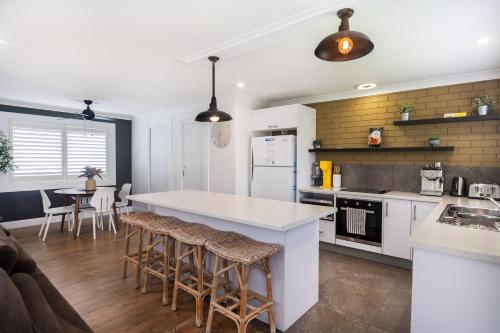 una cocina con encimera blanca y taburetes. en Trifecta House, en Mollymook