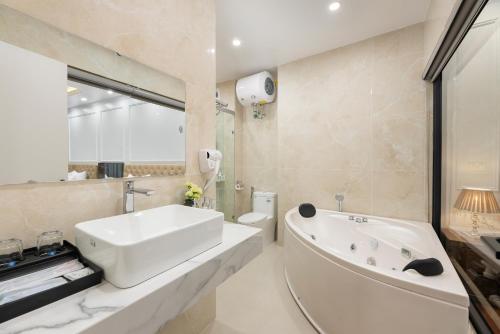 a white bathroom with a tub and a sink at Success Airport Hanoi Hotel in Phu Lo Dong
