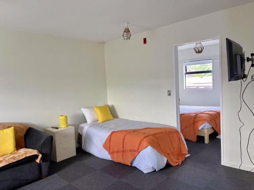 a bedroom with a bed and a tv and a couch at AAA Northlands Motel in Christchurch