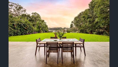 a dining room table with chairs and a green field at Luxury on Lake Tinaroo Lakefront Living in Yungaburra