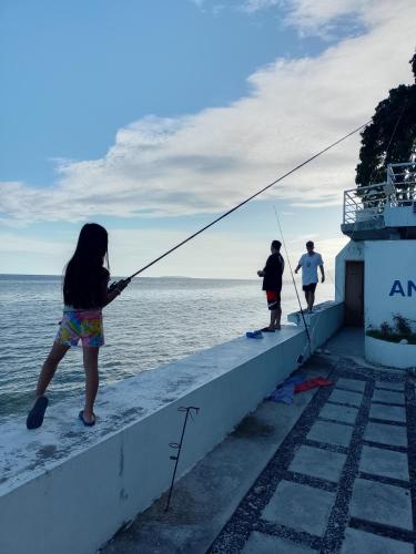 a girl standing on the edge of a pier holding a fishing pole at Angler's Hub & Resort Oslob in Oslob