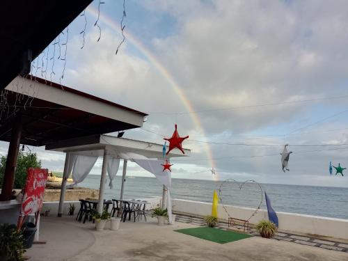 a rainbow in the sky over the beach at Angler's Hub & Resort Oslob in Oslob