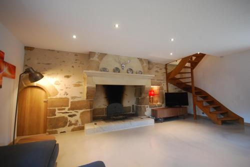 a living room with a fireplace and a staircase at Luxury Farmhouse Brittany in Plénée-Jugon