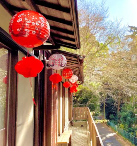 a group of red paper lanterns hanging from a window at #熱海古民家 #来宮神社 バーベキュー温泉 in Atami