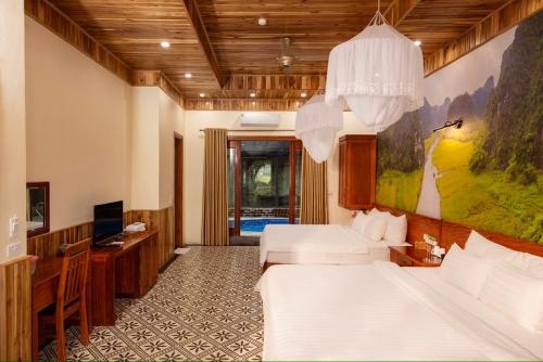 a bedroom with a bed and a desk and a television at Hang Mua Ecolodge in Ninh Binh