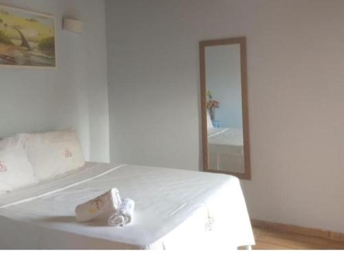 a white bedroom with a bed and a mirror at El Farol Bistrô e Pousada in Fortim