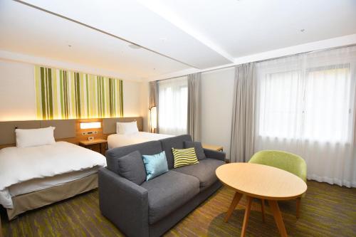 a hotel room with a couch and a bed at Holiday Inn Resort Shinano-Omachi Kuroyon by IHG in Omachi