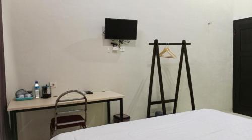 a bedroom with a bed and a desk and a tv at GRAND KHALIFAH Guesthouse in Sumbawa Besar