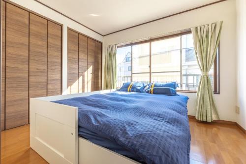 a bedroom with a large bed with blue sheets at Uhome Haneda Apartment in Tokyo