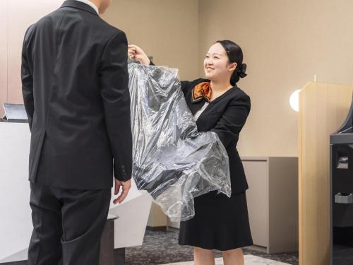 a woman standing next to a man in a suit at Richmond Hotel Obihiro Ekimae in Obihiro
