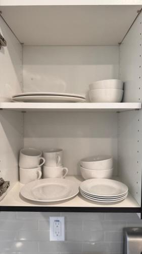 a white cabinet filled with plates and bowls and dishes at Wallace Luxurious in Los Angeles