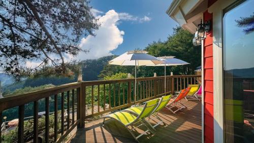 a deck with chairs and an umbrella on a house at Hoengseong Couple Star in Porest Pension in Hoengseong