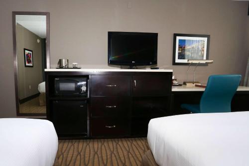 a hotel room with a desk with a television and a bed at Wyndham Garden Westlake in Westlake