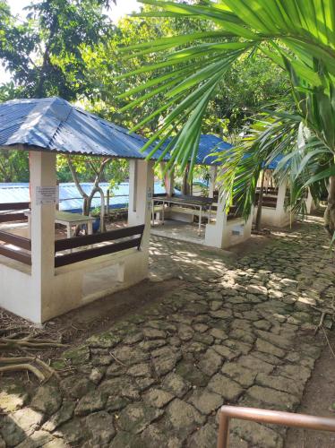 a group of picnic tables with a blue umbrella at Manalo Resort Hotel in Tutulo