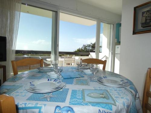 - une table avec des verres et des assiettes avec vue dans l'établissement Appartement T2 à Notre-Dame-de-Monts, balcon, parking, accès plage - FR-1-540-191, à Notre-Dame-de-Monts