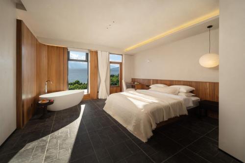a bedroom with a tub and a bed and a sink at Erhai Seaview Garden Villa &Dali Airport in Dali