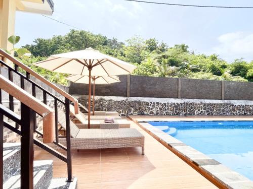 a patio with an umbrella and chairs next to a swimming pool at Kelingking Garden Villa in Nusa Penida