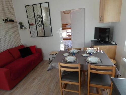 un salon avec une table et un canapé rouge dans l'établissement Maison de Vacances Spacieuse, Proche Forêt, 5 Pers., Terrasse & Parking, Notre-Dame-de-Monts - FR-1-540-280, à Notre-Dame-de-Monts