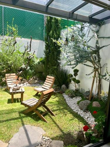 a garden with two wooden chairs and a rock path at Casa Romelia in Acatepec