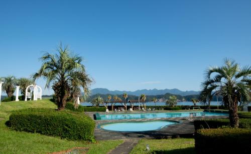 a swimming pool with palm trees and a body of water at Hana Irodori no Yado Kayuu in Taiji