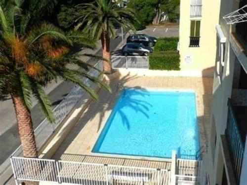 - une piscine à côté d'un bâtiment avec un palmier dans l'établissement Appartement 3 pièces pour 4 avec piscine, terrasse et parking privé à 400m de la plage à Argelès-sur-Mer - FR-1-776-21, à Argelès-sur-Mer