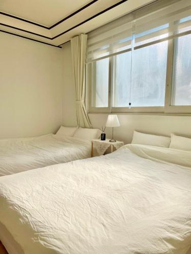 two beds in a bedroom with a window at Slow Stay, #SK Hynix#5 minutes to Chungnam National University#10 minutes to Terminal#Hotel Bedding in Cheongju