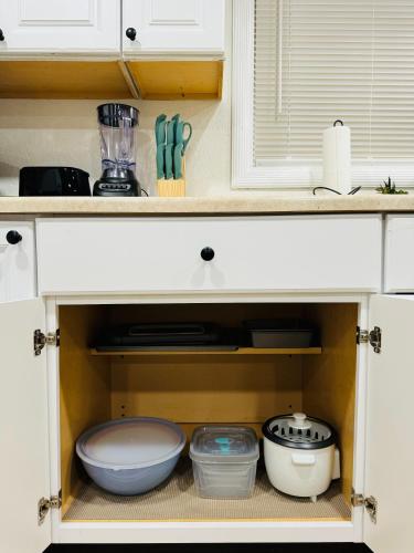 a kitchen cabinet filled with bowls and utensils at Contemporary Studio Near Mojave Aerospace Airport in Mojave