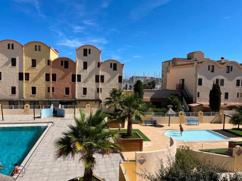 un complexe avec une piscine et quelques bâtiments dans l'établissement Gruissan: T2 Cabine, Piscine, Parking, Centre, 4/5 pers, Petit Budget - FR-1-796-3, à Gruissan