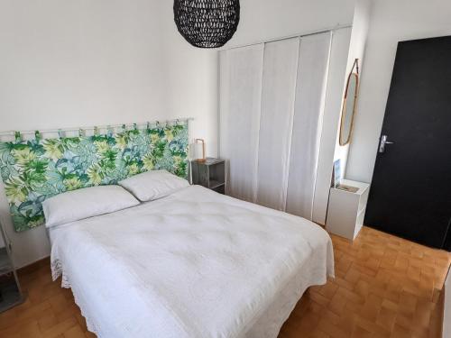 une chambre avec un lit blanc et un mur dans l'établissement Bel appartement T2 climatisé avec piscine et parking à 250m de la plage - FR-1-797-9, à Port-la-Nouvelle