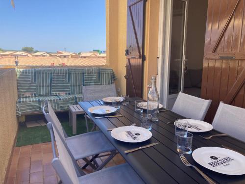- une table en bois avec des assiettes et des verres sur la terrasse dans l'établissement Gruissan: T2 Mezzanine 6 pers, proche plage, parking privé - FR-1-796-35, à Gruissan
