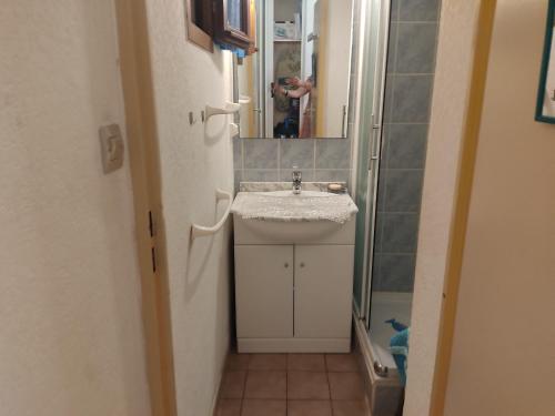 une personne prenant une photo d'une salle de bains avec lavabo dans l'établissement Appartement T2 Climatisé à Gruissan - Piscine, Plage, Parking & Terrasse - Idéal Familles 4/5 pers. - FR-1-796-45, à Gruissan