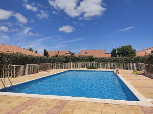 - une piscine avec des personnes assises dans l'eau dans l'établissement Villa 6 pers avec Piscine, Accès direct Plage & Proximité Commerces à Gruissan - FR-1-796-69, à Gruissan