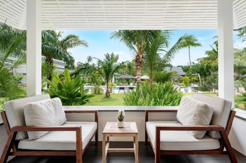 a porch with two chairs and a table and palm trees at Moorea Boutique Resort Samui in Ban Tai
