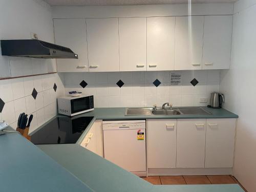 a kitchen with white cabinets and a sink at Placid Waters Holiday Apartments in Bongaree