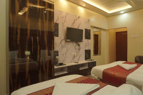Una habitación de hotel con dos camas y un televisor. en Classy5 Guest House, en Varanasi