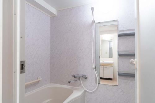a bathroom with a shower and a tub and a sink at Daffitto Tennozu in Tokyo