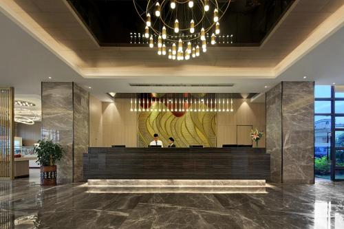 a lobby of a hotel with a reception desk and a chandelier at 汉永瑞酒店深圳宝安机场店 in Bao'an