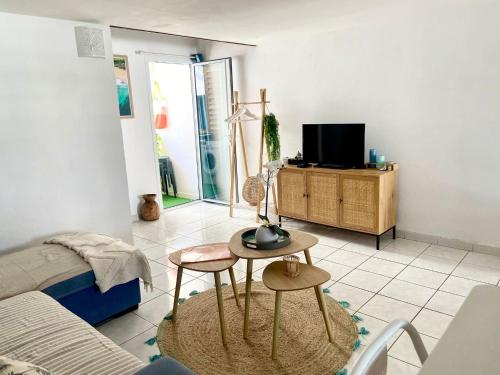 a living room with a table and two chairs and a tv at Ti Lamp Ti Lamp: Cocon de Sérénité Près de la Mer in Saint-Paul