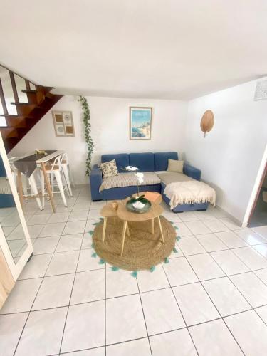 a living room with a blue couch and a table at Ti Lamp Ti Lamp: Cocon de Sérénité Près de la Mer in Saint-Paul