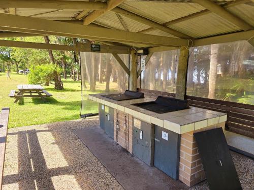 an outdoor kitchen with a picnic table in a park at Camp Elim in Forster