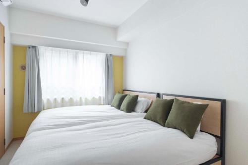 a large white bed in a room with a window at Daffitto Tennozu in Tokyo