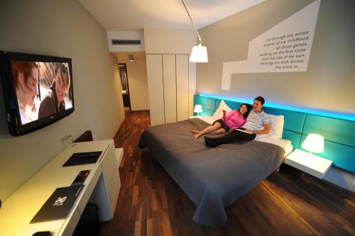 a woman sitting on a bed watching tv at MOODs boutique hotel in Prague