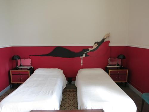 two beds in a room with a woman jumping on the wall at Maison Decò in Catania