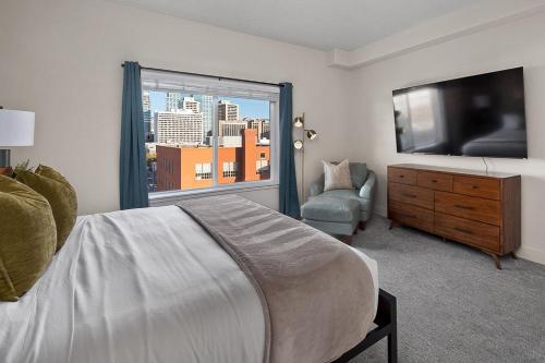 a bedroom with a bed and a television and a chair at Convention Ctr - Stylish 2BD,2BA with Pool,Gym and Hot tub in Salt Lake City
