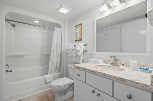 a white bathroom with a toilet and a sink at Oceanfront Ocean Pearl in Myrtle Beach in Myrtle Beach