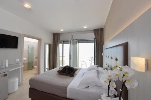 a bedroom with a bed with white sheets and flowers at Hotel Globus in Bellaria-Igea Marina