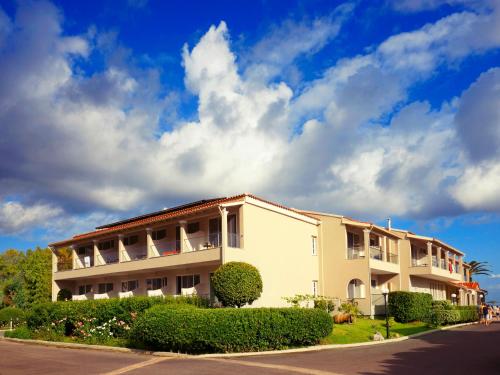 a building on a street with a cloudy sky at Acharavi Beach Hotel in Acharavi